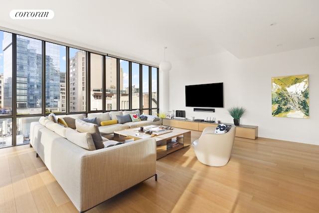 living room featuring light wood-type flooring and floor to ceiling windows