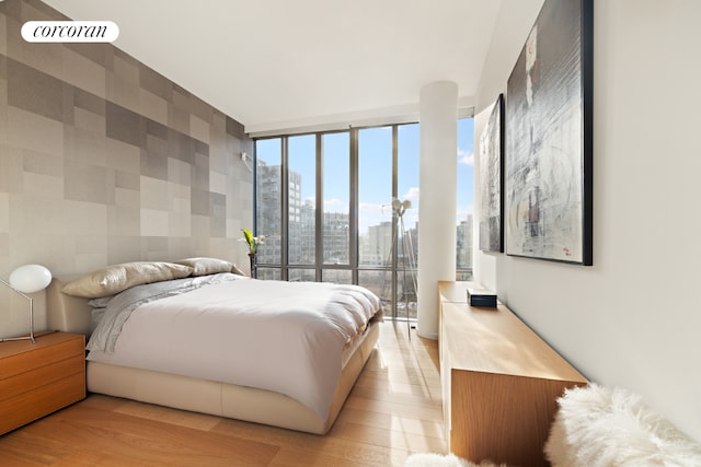 bedroom with light wood-type flooring and floor to ceiling windows