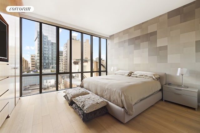 bedroom with a wall of windows and light hardwood / wood-style floors