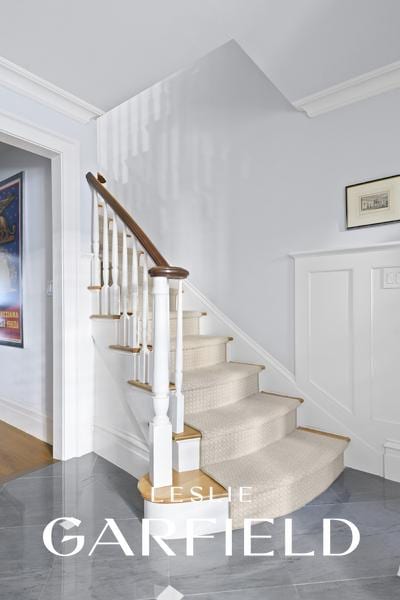 stairs featuring crown molding and a decorative wall