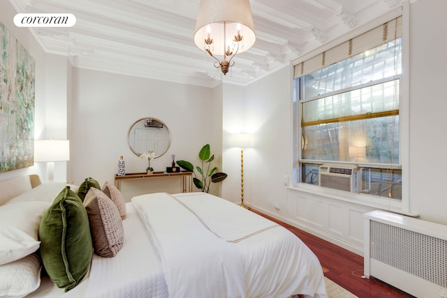 bedroom featuring radiator heating unit, an inviting chandelier, wood finished floors, and crown molding