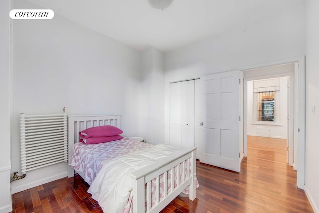 bedroom featuring visible vents, radiator heating unit, a closet, and hardwood / wood-style flooring