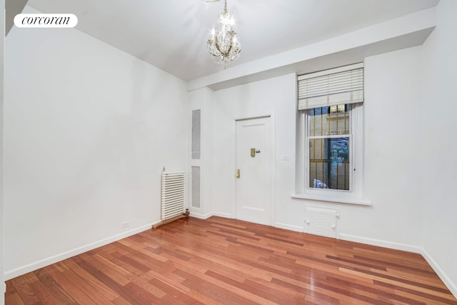 unfurnished room featuring baseboards, a notable chandelier, visible vents, and wood finished floors