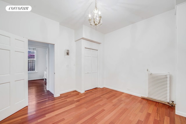 spare room featuring baseboards, visible vents, light wood finished floors, and an inviting chandelier