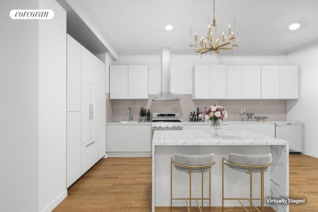 kitchen with stainless steel stove, sink, white cabinets, white dishwasher, and wall chimney exhaust hood