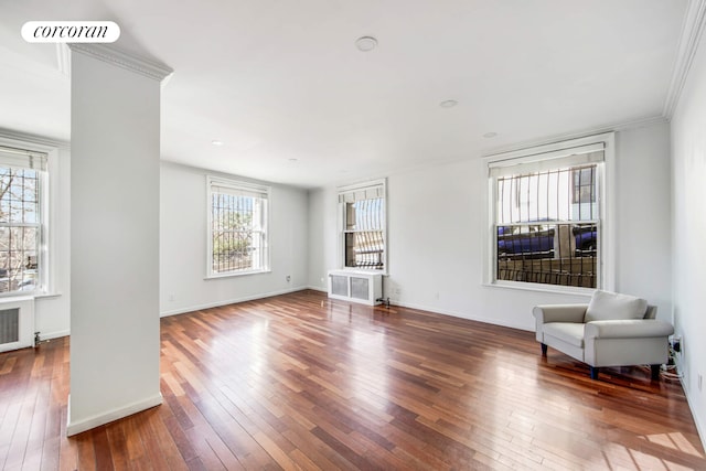 interior space with radiator, wood-type flooring, visible vents, ornamental molding, and baseboards