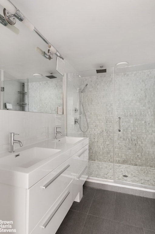 bathroom with walk in shower, vanity, tile walls, tasteful backsplash, and tile patterned floors