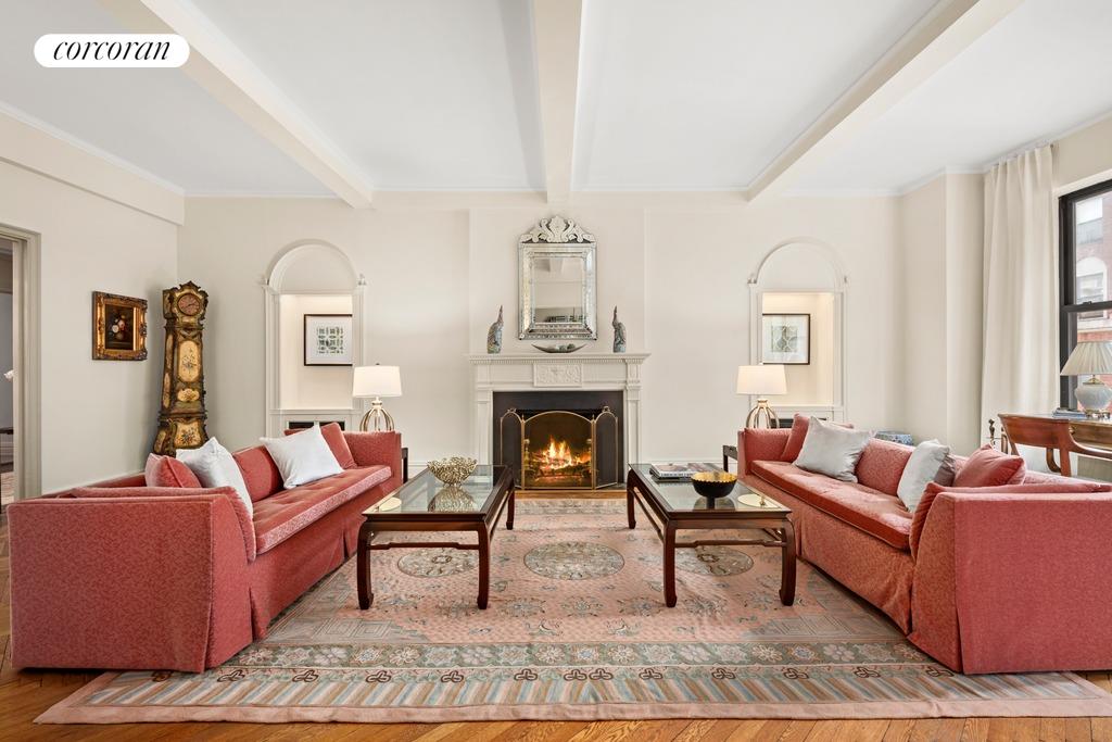 living area featuring a warm lit fireplace, beam ceiling, wood finished floors, and visible vents