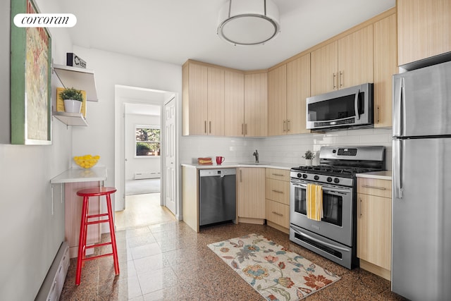 kitchen featuring light brown cabinets, light countertops, baseboard heating, stainless steel appliances, and a sink