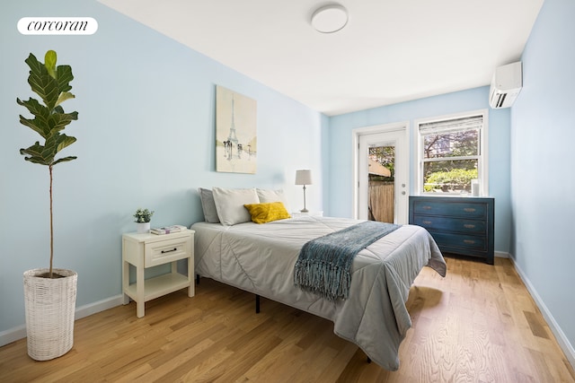 bedroom with visible vents, baseboards, an AC wall unit, light wood-type flooring, and access to outside