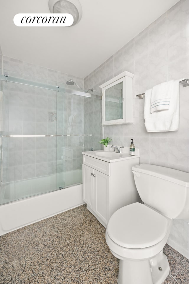 full bath featuring tasteful backsplash, toilet, vanity, shower / bath combination with glass door, and tile walls