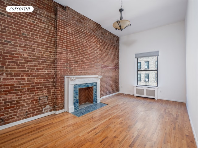 54 W 71st Street Building, New York City, NY 10023 - unfurnished living room with brick wall, a fireplace with flush hearth, radiator heating unit, hardwood / wood-style floors, and baseboards
