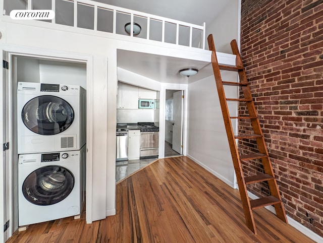 54 W 71st Street Building, New York City, NY 10023 - laundry area with stacked washer / drying machine, dark wood finished floors, brick wall, and baseboards
