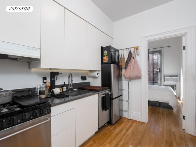 bedroom with hardwood / wood-style flooring, access to exterior, radiator heating unit, and a wall mounted air conditioner