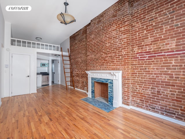 unfurnished living room with light hardwood / wood-style floors and brick wall