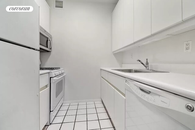 kitchen featuring visible vents, white appliances, white cabinets, and a sink
