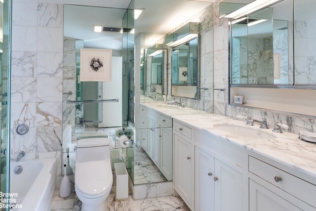 bathroom featuring vanity, toilet, a bath, and tile walls