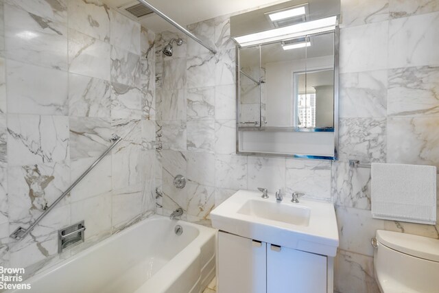 full bathroom featuring vanity, tile walls, toilet, and shower / bath combination