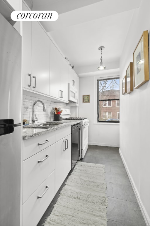 kitchen with pendant lighting, sink, white appliances, white cabinets, and decorative backsplash