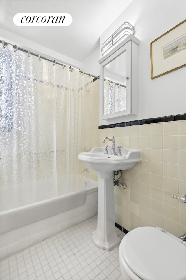 bathroom featuring tile patterned flooring, wainscoting, toilet, tile walls, and shower / bath combo