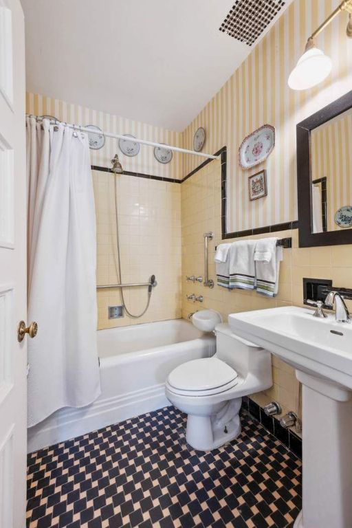 bedroom with radiator heating unit, vaulted ceiling with skylight, light hardwood / wood-style flooring, and an AC wall unit