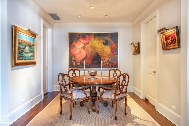 dining space featuring dark wood-type flooring, visible vents, ornamental molding, and baseboards