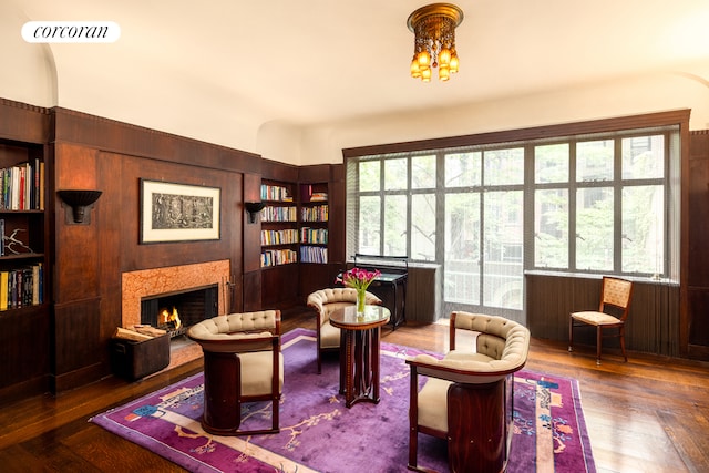 49 E 80th St, New York City, NY 10075 - sitting room featuring visible vents, built in shelves, an inviting chandelier, wood finished floors, and a lit fireplace