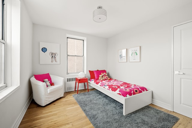 bedroom featuring radiator, baseboards, and wood finished floors