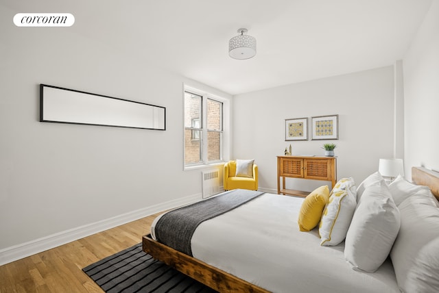 bedroom with radiator, baseboards, visible vents, and wood finished floors