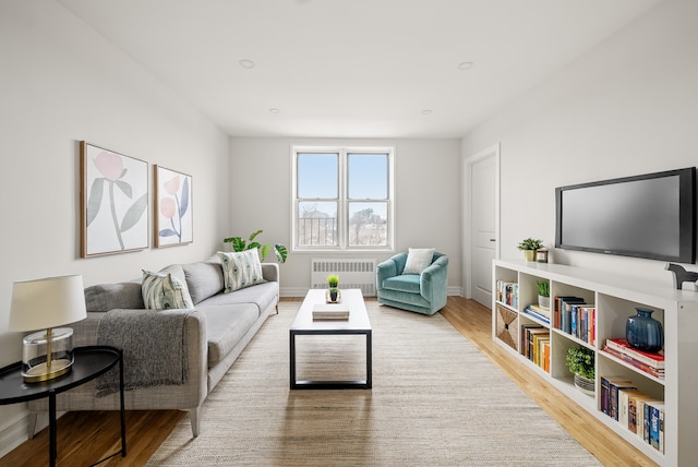 living area with radiator heating unit, wood finished floors, and baseboards