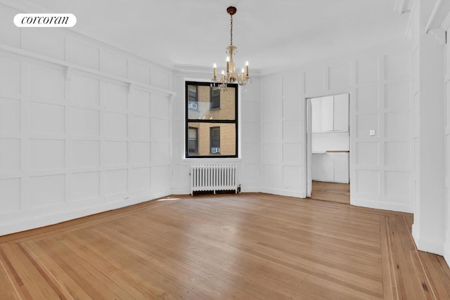 spare room featuring hardwood / wood-style floors, a chandelier, and radiator heating unit