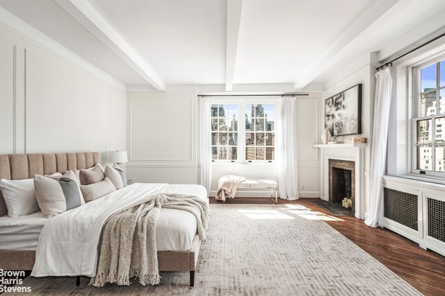 living room featuring a healthy amount of sunlight, hardwood / wood-style flooring, radiator heating unit, and beamed ceiling