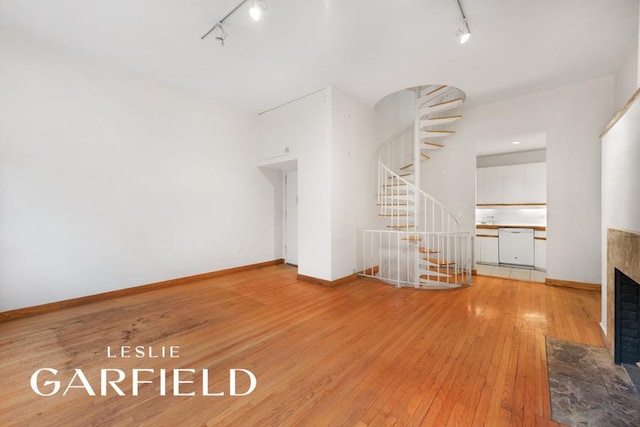 unfurnished living room featuring rail lighting and light hardwood / wood-style flooring