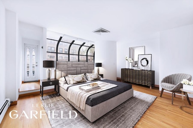 bedroom with a baseboard radiator and hardwood / wood-style floors