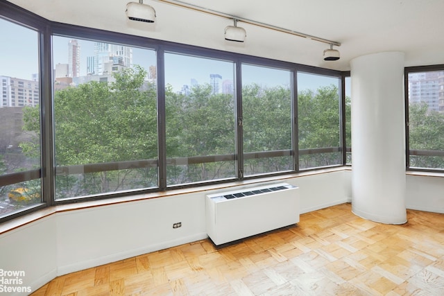 unfurnished sunroom with radiator and track lighting