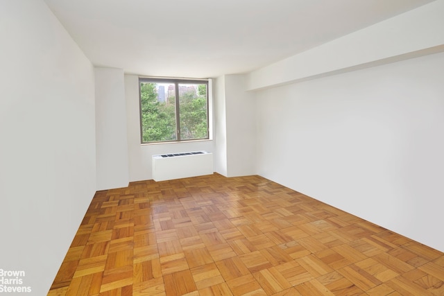 spare room with radiator heating unit and light parquet floors