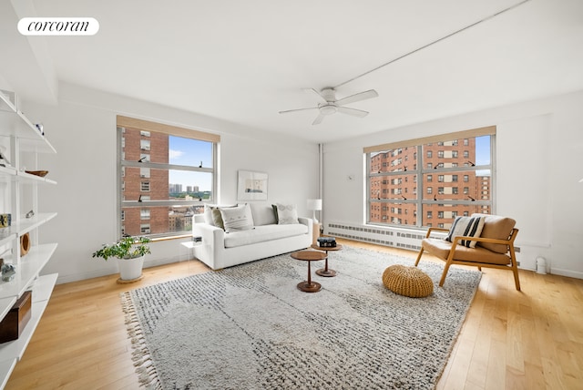 living room with a baseboard radiator, ceiling fan, and light wood-type flooring