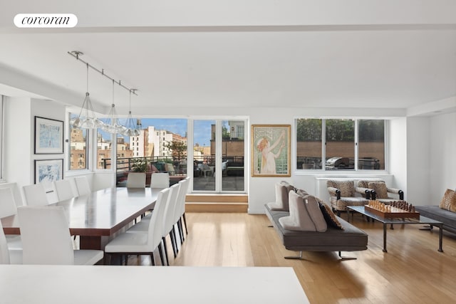 dining area with rail lighting, visible vents, a notable chandelier, and light wood-style flooring