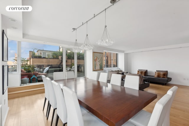 dining space featuring a chandelier, rail lighting, visible vents, and light wood-style floors