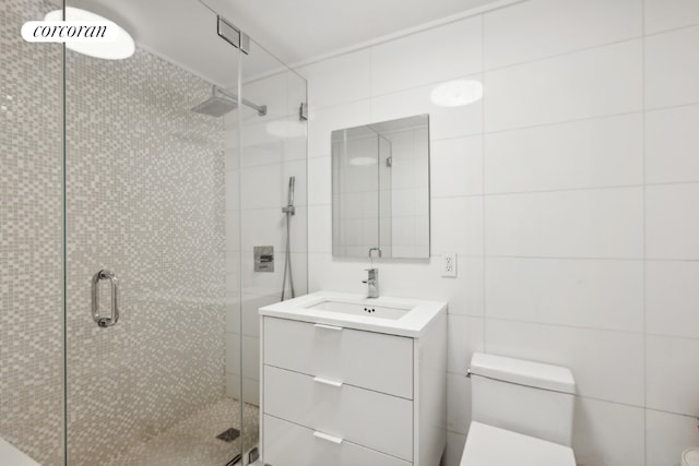 full bathroom with tile walls, a shower stall, toilet, and vanity