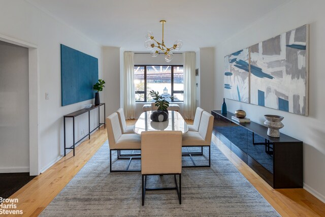 425 E 58th St Unit 4H, New York City, NY 10022 - dining space featuring wood finished floors, a chandelier, and baseboards