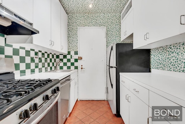 kitchen featuring light tile patterned flooring, sink, white cabinetry, stainless steel appliances, and backsplash