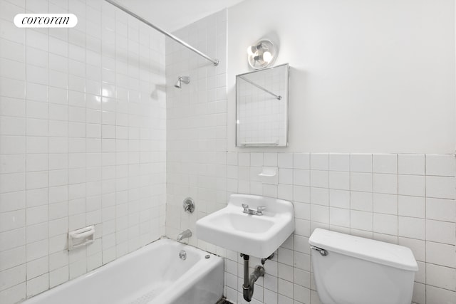 bathroom featuring toilet, tile walls, and shower / washtub combination