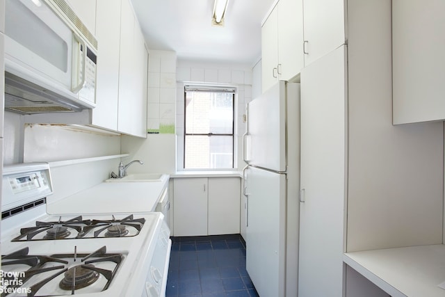 kitchen with white appliances, sink, and white cabinets