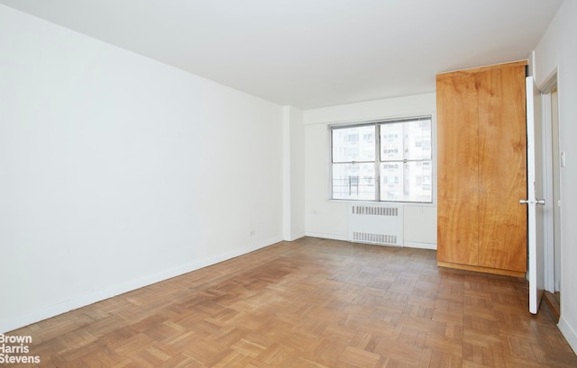 empty room featuring radiator and parquet floors