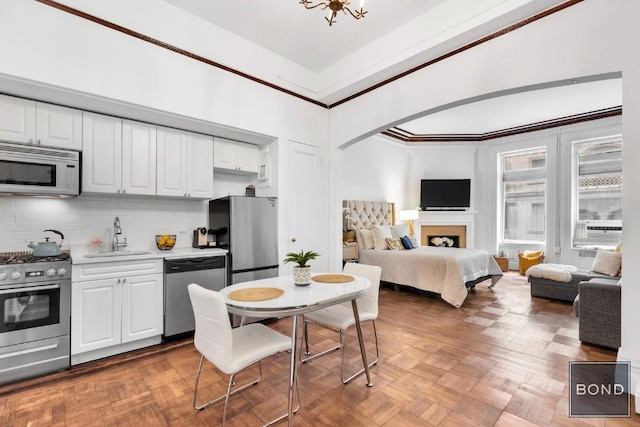 kitchen featuring sink, white cabinets, appliances with stainless steel finishes, and parquet floors