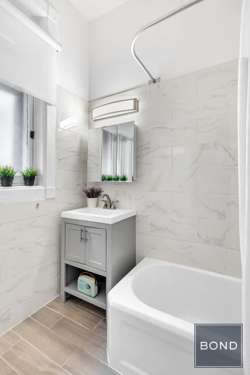 bathroom with tile walls, vanity, and shower / bathing tub combination