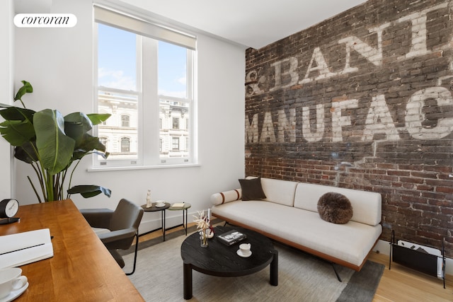 interior space with light wood-style floors, brick wall, and baseboards