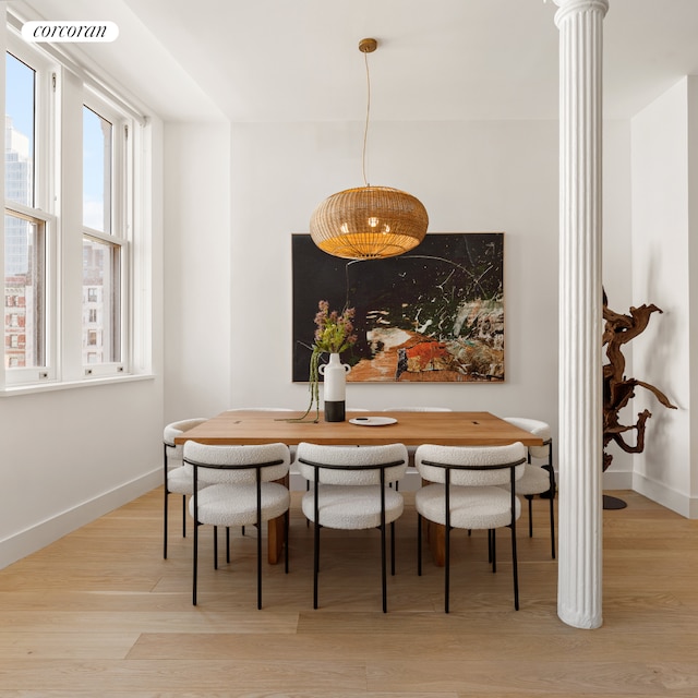 dining room featuring ornate columns, visible vents, baseboards, and wood finished floors