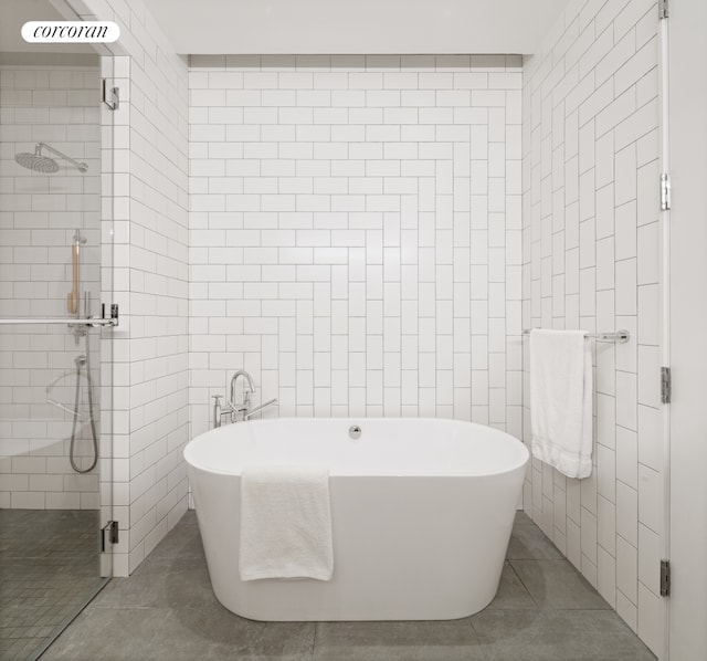 bathroom featuring a freestanding bath, tiled shower, tile walls, and tile patterned floors